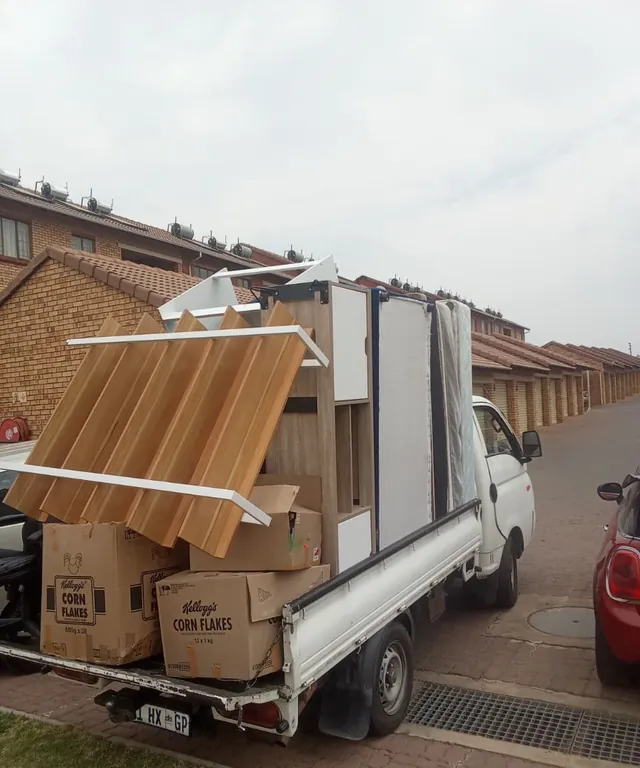 A Lewin Projects bakkie loaded with flat-pack furniture and boxes outside a townhouse complex