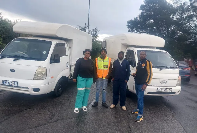 The Lewin Projects and Logistics team standing in front of two loaded bakkies before a job