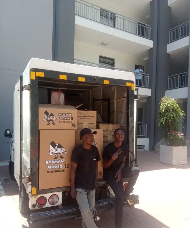 Two Lewin Projects movers loading packed boxes into a removal truck outside an apartment block in Gauteng