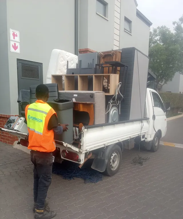 Office furniture being carefully loaded onto a Lewin Projects bakkie during a commercial relocation