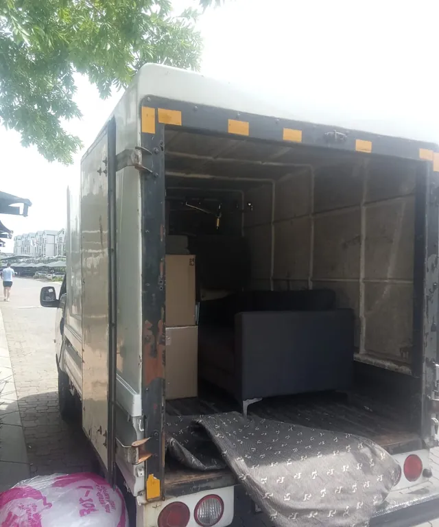 The open rear of a Lewin Projects truck with furniture loaded and a tail lift lowered