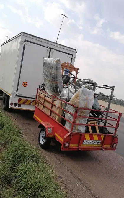 Wrapped and stacked furniture secured on a Lewin Projects trailer behind a removal truck